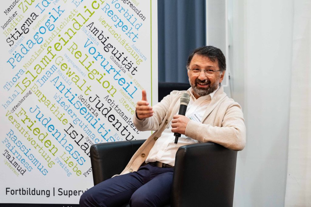 Mustafa Cimşit – sitzend während Vortrag